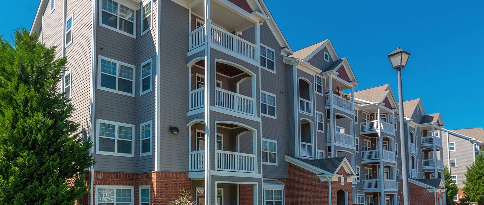 the exterior of an apartment building with a large lawn at The Leyland Pointe